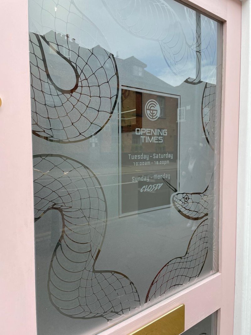 Etched snake window graphic with opening times, shop door vinyl by Lauryn Jaime Ltd